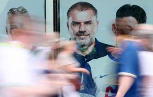 Fans of Tottenham Hotspur walk past a giant picture of Ange Postecoglou,
