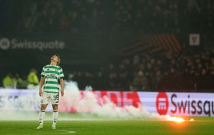 Daizen Maeda of Celtic reacts as a flare falls onto the pitch