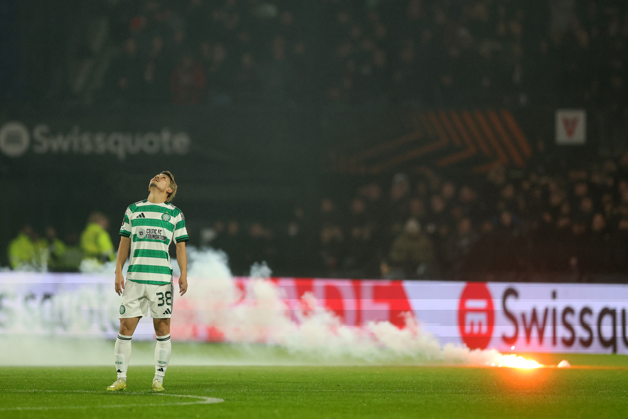 Daizen Maeda of Celtic reacts as a flare falls onto the pitch