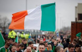 A Celtic fan flies an Irish Tricolour on the way to Ibrox on Beautiful Sunday