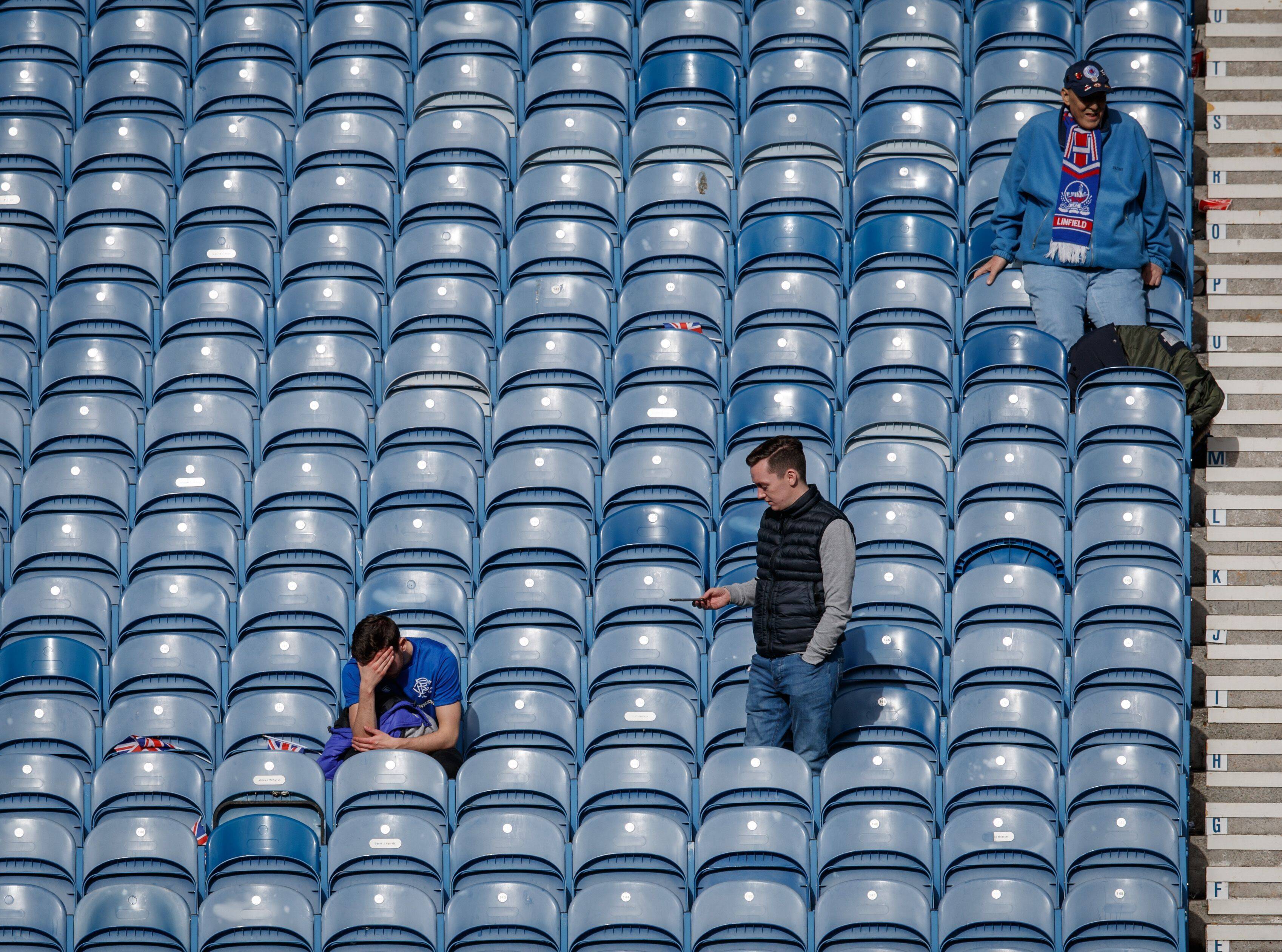 A dejected fan of theRangers sits with his head in his hands in the Govan Stand