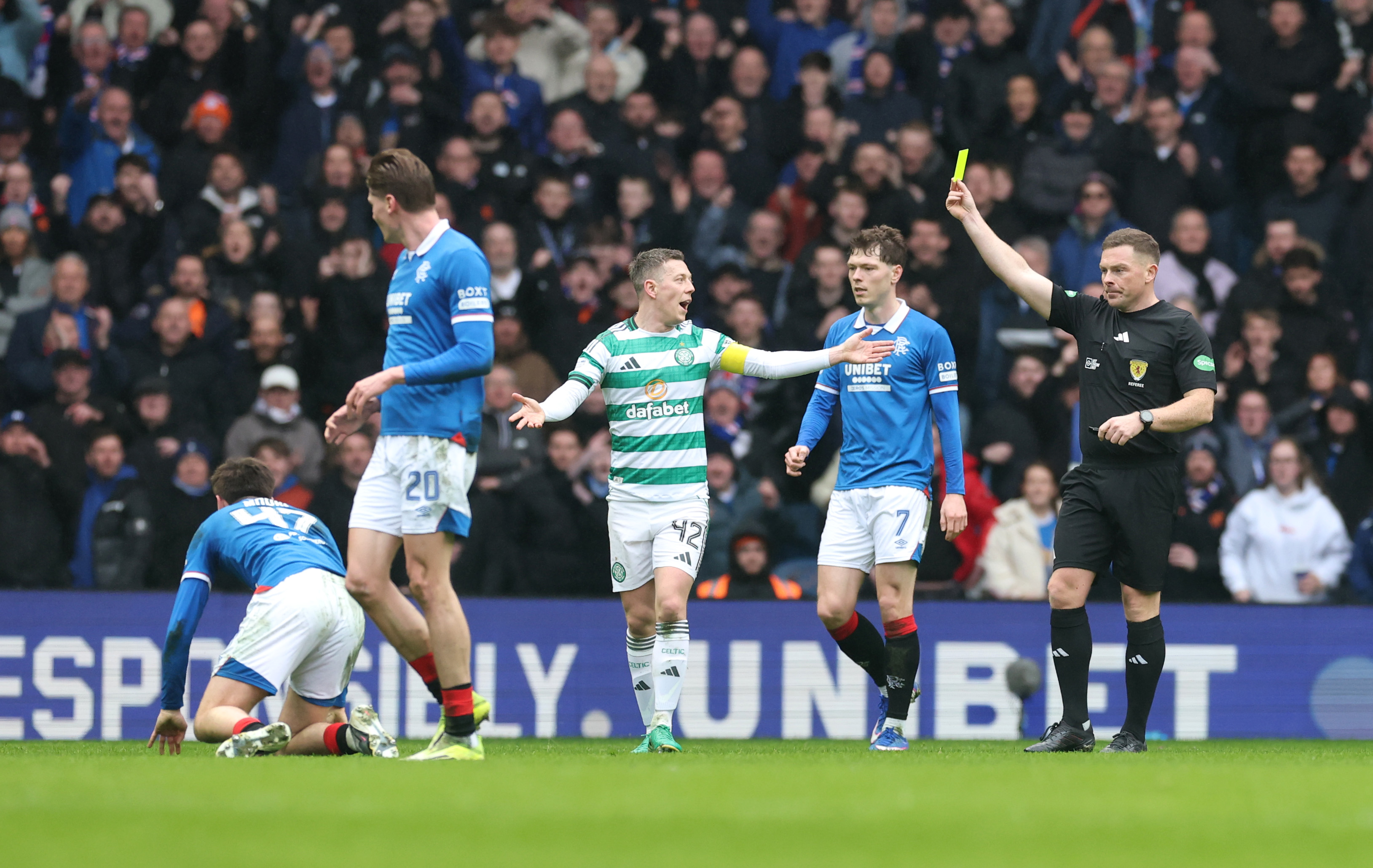 Callum McGregor of Celtic reacts as he is shown a yellow card by referee John Beaton